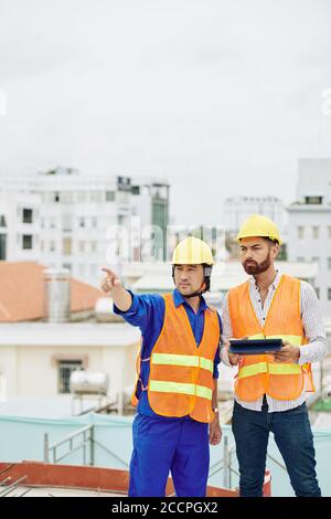 Appaltatore che mostra i lavori finiti al capo inginconio ingegnere del progetto con il tablet digitale nelle mani Foto Stock