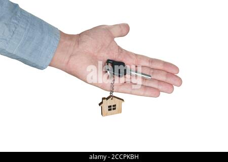Mano di un agente immobiliare che tiene una chiave di casa, isolato su sfondo bianco. Concetto di acquisto di proprietà. Portachiavi in legno di palma. Vendita di Foto Stock