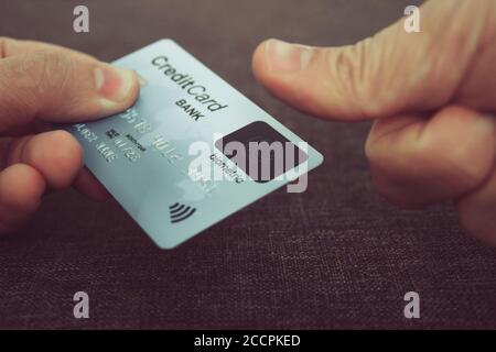 Primo piano di mani maschili che tengono la carta di credito con lettore di impronte digitali e incorporano il pollice per pagare online. Concetto di utilizzo della tecnologia biometrica in Foto Stock