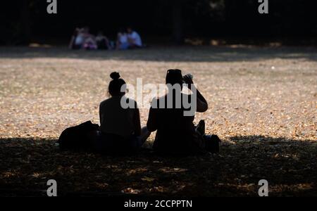 12 agosto 2020, bassa Sassonia, Osnabrück: Due donne siedono in un parco all'ombra degli alberi per proteggersi dal caldo. Uno di loro sta bevendo da una bottiglia di acqua. Foto: Frito Gentsch/dpa Foto Stock