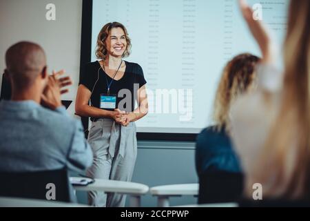 Team di professionisti che si battono le mani in una riunione per una presentatrice femminile. Gli uomini d'affari apprezzano la presentazione di una collega. Foto Stock