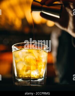 Il barman versa il whisky al bar. Foto Stock
