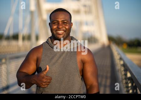 Ritratto di giovane allegro afroamericano in abbigliamento sportivo che guarda la macchina fotografica e sorridente. Foto Stock