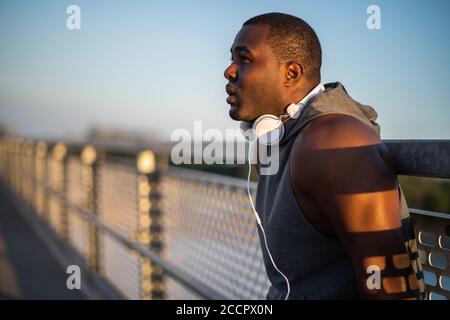 Ritratto di giovane allegro afroamericano in abbigliamento sportivo che si rilassa dopo il jogging.