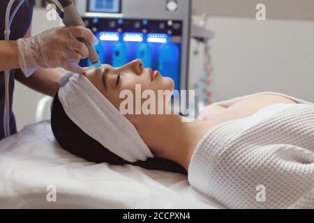Vista laterale della donna che riceve la terapia di microdermabrasion sulla fronte alla beauty spa. Procedura Hydracial in clinica di Cosmetologia. Foto Stock