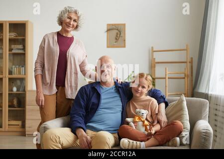 Ritratto di coppia senior moderna sorridente a macchina fotografica mentre si posa in casa accogliente interno con cute capelli rossi ragazza, copia spazio Foto Stock