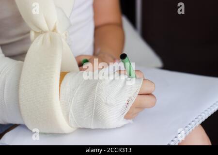 Bambina con mano in cast, cercando di disegnare, recupero Foto Stock