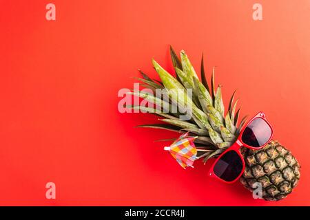 Festeggia l'estate concetto di Pineapple Day, vista dall'alto piatto di divertente ananas indossare occhiali da sole rossi, studio girato isolato su sfondo rosso, Holiday summ Foto Stock