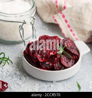 Beet (barbabietola) biologico sano al forno viola con olio d'oliva, sale marino grande e rosmarino in una ciotola bianca su uno sfondo grigio di cemento da vicino. Foto Stock