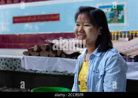 Ritratto di una donna thanaka venditore ad un tempio buddista. Pasta Thanaka sul viso usata come cosmetica e repellente per zanzare. Sorridente birmana. Myanmar Foto Stock