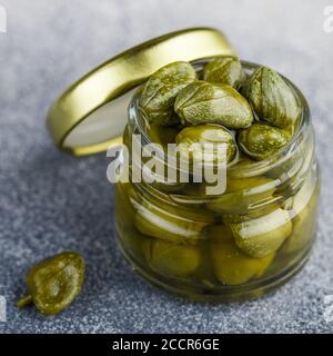 Capperi decapati o salati in un vaso di vetro da vicino. Boccioli di fiori non aperti. Ingredienti deliziosi per cucinare i cuis mediterranei, italiani, spagnoli, francesi Foto Stock