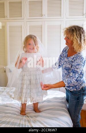 Bambino giovane femmina 3 anni vestirsi in un vecchio abito da sposa originariamente indossato da sua nonna 56 anni prima Foto Stock