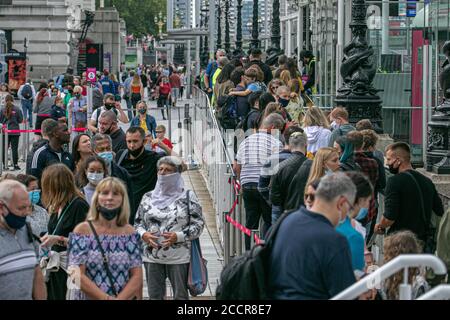 WESTMINSTER LONDRA, Regno Unito - 24 agosto 2020 turisti e turisti che indossano una coda di mascherine protettive per il London Eye che ha riaperto dopo che le restrizioni di blocco del coronavirus sono state attenuate. I visoter devono avere la loro temperatura presa aprior per entrare ed aderire alle linee guida rigorose di distanziamento sociale. Credit: amer Ghazzal/Alamy Live News Foto Stock