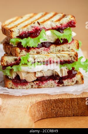 Delizioso sandwich di tacchino o pollo con brie o Camembert formaggio, lattuga e mirtillo (lingonberry, bacca di gallina) chutney sul pane di grano con lino vedere Foto Stock