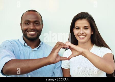 La coppia nera sta mostrando un cuore. L'uomo e la donna stanno facendo il cuore con le dita. Foto Stock