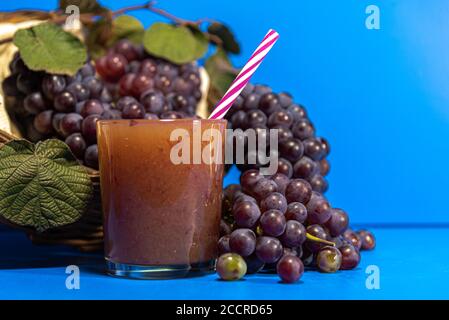 Succo d'uva in un bicchiere. Grappoli di uva della specie niagara (Vitis labrusca "Niagara"). Sfondo blu. Bevanda rinfrescante. L'uva niagara è accesa Foto Stock