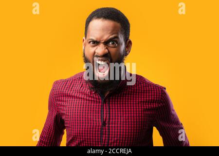 Arrabbiato afro uomo urlando allo studio giallo Foto Stock