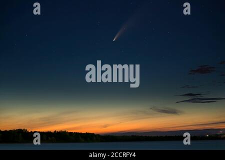 La cometa luminosa Neoswise vola in alto nel cielo estivo Sopra il bagliore di una città vicina in Canada Foto Stock
