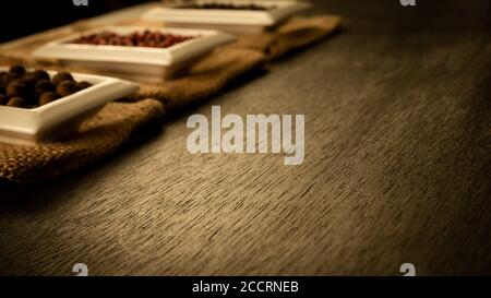 Ciotola piena di spezie sul burlap e su uno sfondo di legno scuro. Spezie naturali, vecchio tema di stagionatura vintage. Spazio di copia per il testo. Spazio di copia per il prodotto. Foto Stock