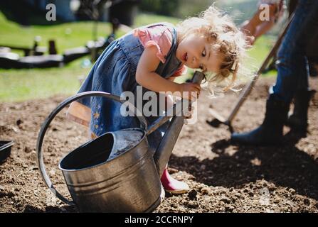Piccola ragazza che gioca all'aperto in giardino, concetto di stile di vita sostenibile. Foto Stock