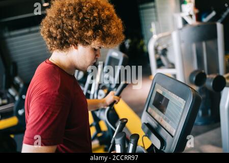 Giovane uomo in sovrappeso che si esercita in palestra per raggiungere gli obiettivi Foto Stock