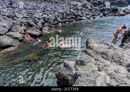 Ponta da Ferraria, Azzorre, Portogallo - 13 agosto 2020: Persone che nuotano in una piscina termale vulcanica naturale a Ponta da Ferraria, il luogo dove si sprin caldo Foto Stock