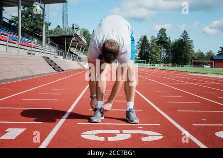uomo che si prepara a correre su una pista da corsa Foto Stock