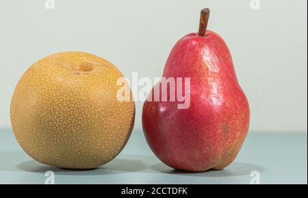 Frutta fresca di pera. Pere asiatiche (Pyrus pirifolia) e rosse (Pyrus communis 'Williams'). Cibo naturale. Frutta per succhi e marmellate. Sfondo blu. Foto Stock
