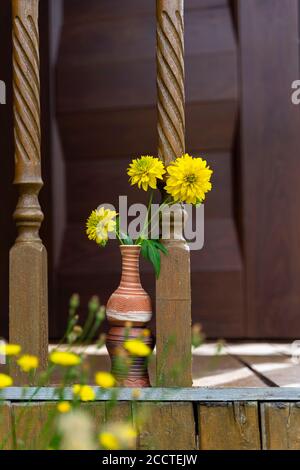 Bouquet di fiori gialli in un vaso di caraffa di argilla uno sfondo di legno Foto Stock