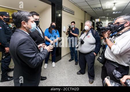 Asuncion, Paraguay. 24 Agosto 2020. Un dipendente del Palazzo di Giustizia (l) indossando una guardia di bocca parla con giornalisti e fotoreporter di fronte alla sala dove l'ex stella brasiliana di calcio Ronaldinho è in prova. Il due volte calciatore del mondo e campione del mondo del 2002 e suo fratello sono stati catturati con falsi documenti di identità paraguaiani poco dopo che sono entrati in Paraguay in marzo e hanno trascorso più di 30 giorni in prigione. Credit: Jorge Candia/dpa/Alamy Live News Foto Stock