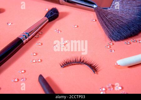 pennelli per il trucco di diverse misure su sfondo pastello, accompagnati da falsi ciglia e piccoli diamanti distribuiti dal set, top e close Foto Stock