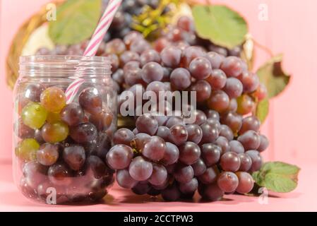 Pentola con grani e grappoli d'uva. Succo d'uva, bevanda rinfrescante. Bevanda di frutta. Ingrediente per vini e succhi. Frutta fresca. Uva rosa. Foto Stock