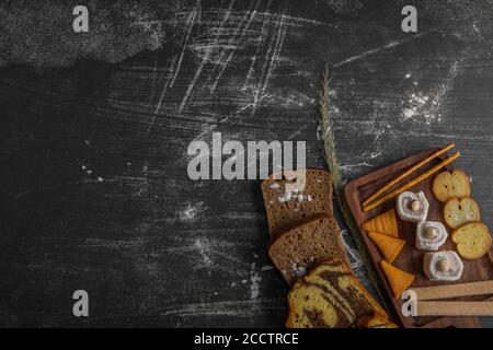 Patatine con prodotti di pasticceria su un piatto di legno e. fette di pane da parte sull'angolo inferiore Foto Stock