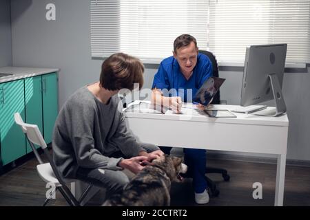 Una persona con un cane da Husky che ha un appuntamento in una clinica di veterinario. Foto Stock