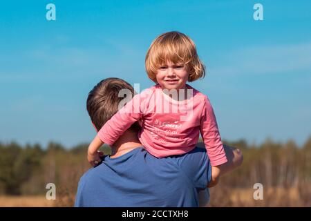 Padre porta la figlia tra le braccia in estate campo Foto Stock