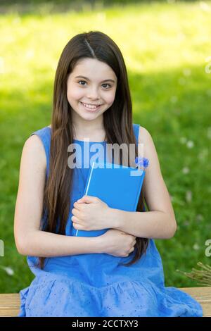 Piccola ragazza intelligente con libro all'aperto giorno di sole, concetto di poesia romantica. Foto Stock