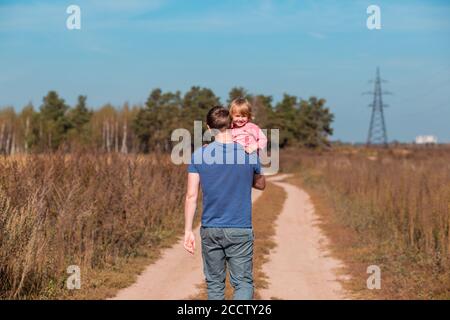 Padre porta la figlia tra le braccia in estate campo Foto Stock