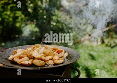 patate fritte con una crosta cucinata in un grande nero panare sulla griglia Foto Stock