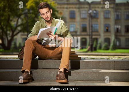 Studente universitario focalizzato che fa i suoi compiti fuori Foto Stock