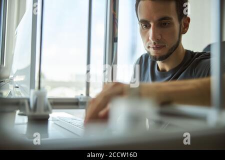 Scienziato maschile focalizzato utilizzando una stampante 3D Foto Stock