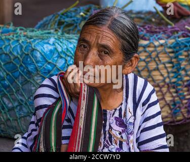 Una donna Maya più anziana di Tzutujil in abito tradizionale vende i prodotti nel mercato settimanale a Santiago Atitlan, Guatemala. Foto Stock