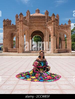 Una giovane donna nel tipico costume da ballo di Chiapa de Corzo si pone di fronte alla fontana la pila. Chiapas, Messico. Foto Stock