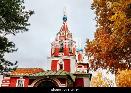 Antica chiesa cristiana e alberi gialli d'autunno. Belle cupole, alto campanile contro il cielo Foto Stock