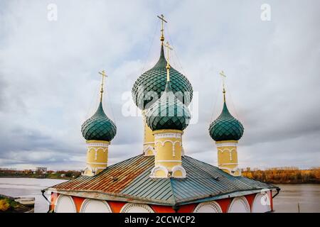 Antica chiesa cristiana e alberi gialli d'autunno. Belle cupole, alto campanile contro il cielo Foto Stock