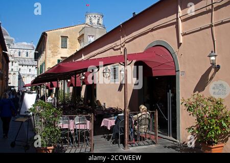 Posti a sedere all'aperto in un ristorante in Via Santa Maria con la Torre Pendente di Pisa alle spalle, Pisa, Toscana, Italia Foto Stock