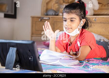 Studentessa ragazzina ragazzina alza la mano mentre studia classe online con tablet a casa, nuovo normal.Covid-19 coronavirus.Social distancing, casa scuola Foto Stock