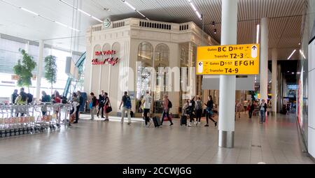 Aeroporto di Schiphol con negozi, cart per bagagli e indicazioni stradali. Amsterdam Paesi Bassi Foto Stock