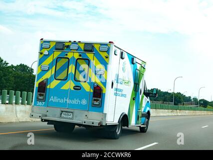 Giallo e blu strisce Alina Salute emergenza servizi medici ambulanza guida in autostrada. Minneapolis, Minnesota, Stati Uniti Foto Stock