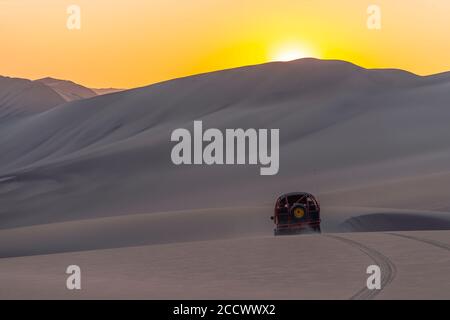 Silhouette di un buggy guida nel deserto costiero peruviano al tramonto tra Ica e Huacachina, Perù. Foto Stock