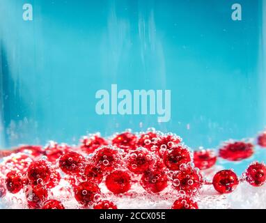 Perline rosse in acqua con bolle, carta di Natale, astrazione Foto Stock